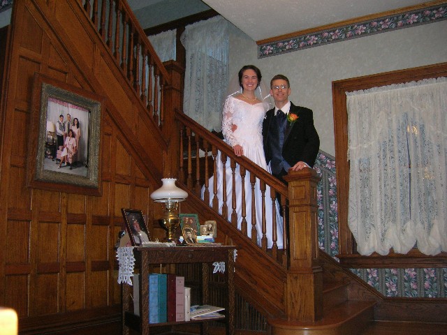 Peter and Tara in their wedding finery on the stairs in Tara's childhood home.